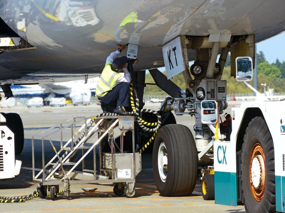 Agent d'escale intervenant sous le fuselage lors d'une opération piste